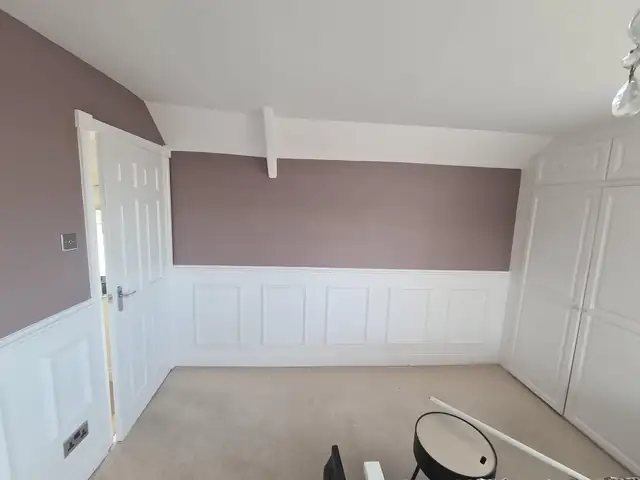 Bedroom with mauve walls above white panelling