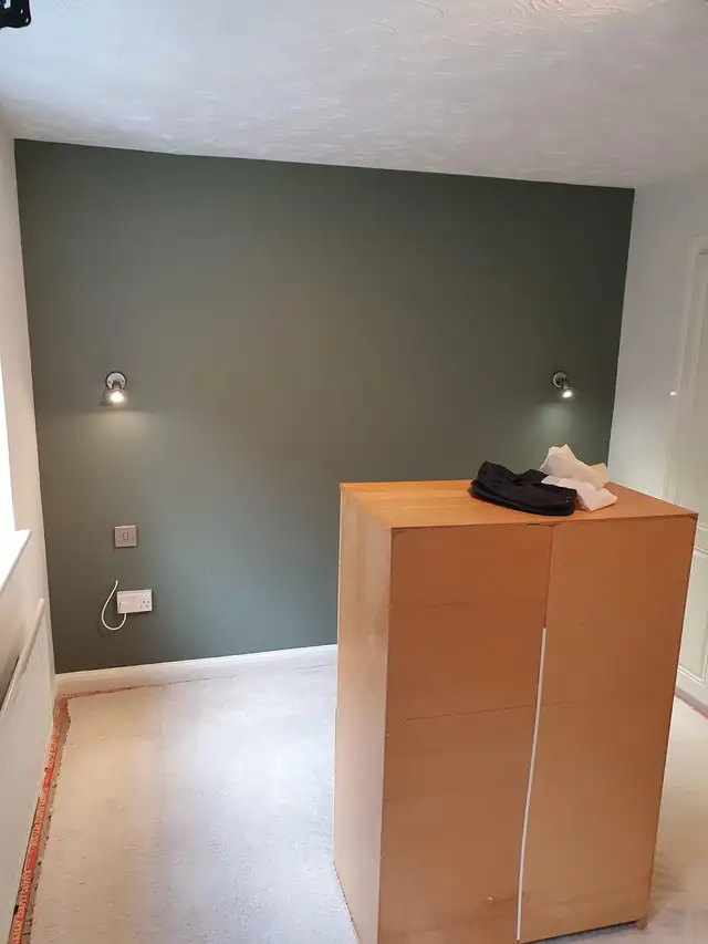Bedroom with a deep green feature wall and white ceiling